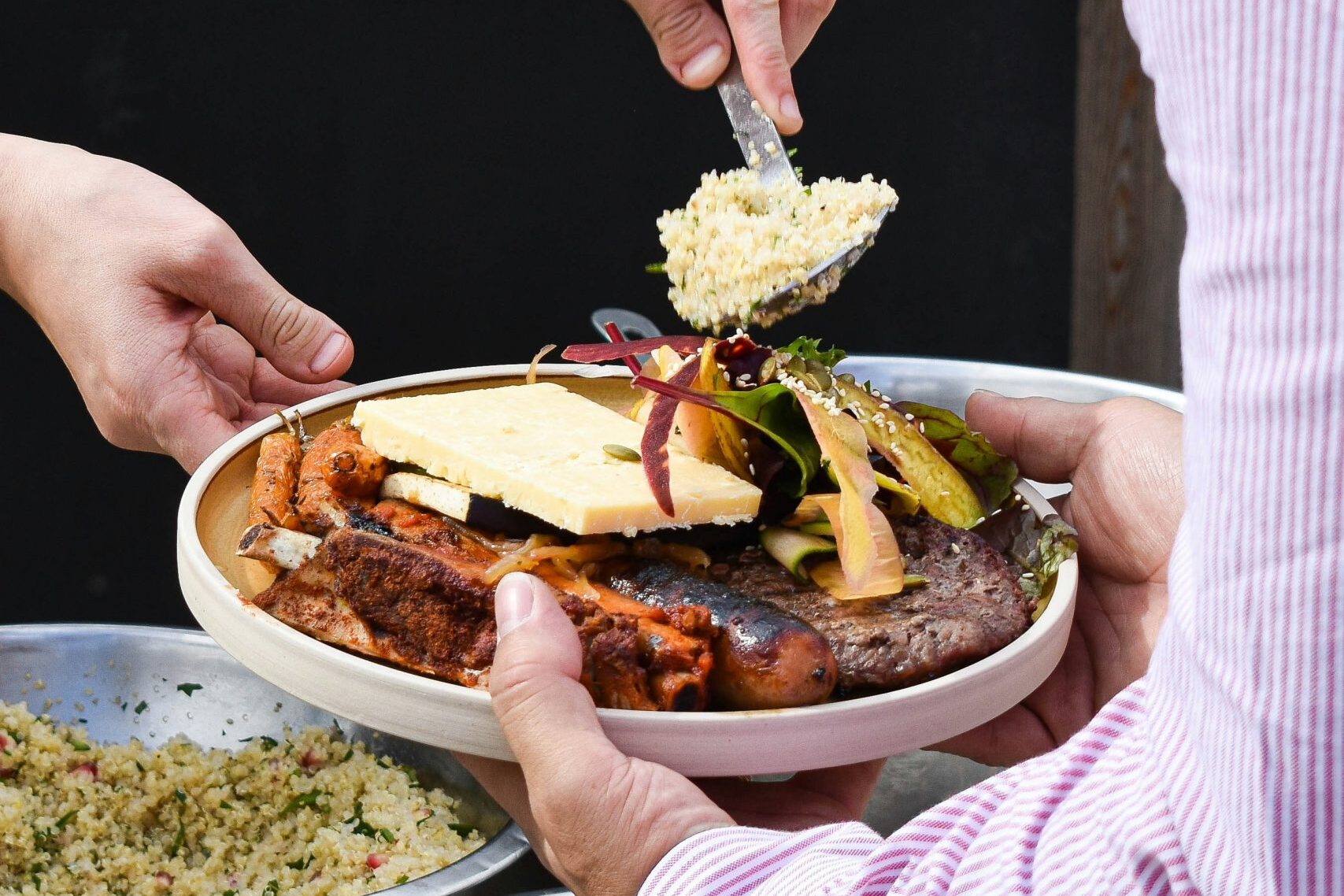 Catering-Mitarbeiter richtet einen Teller am Buffet an und portioniert Beilage bei einem Business-Lunch.